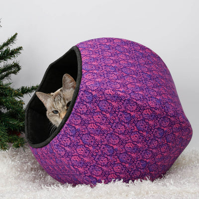 Give your cat an authorized spot under the Christmas tree with the Cat Ball® cat bed! Our innovative cat cave design has two openings, and is made here in a purple and pink foulard, lined with a black print. Made in the USA. 